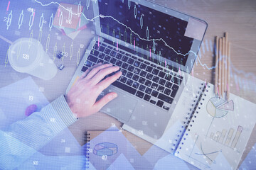 Double exposure of man's hands typing over computer keyboard and forex graph hologram drawing. Top view. Financial markets concept.