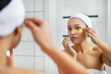 Cute woman puts patches under the eyes in the bathroom. Eye skin beauty