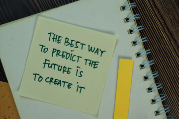 The Best Way To Predict The Future Is To Create It write on a book isolated on Wooden Table.