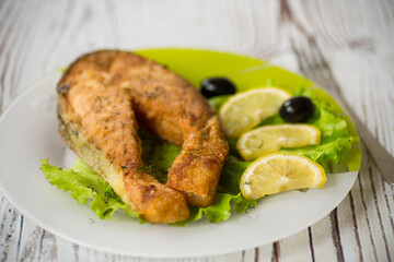 piece of fried salmon fish in a plate with lemon
