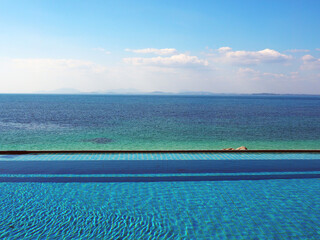 Fototapeta na wymiar sea view swimming pool, blue green ocean and bright blue sky with clouds