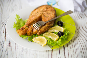 piece of fried salmon fish in a plate with lemon