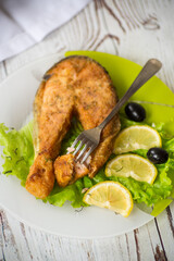 piece of fried salmon fish in a plate with lemon
