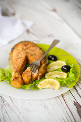 piece of fried salmon fish in a plate with lemon