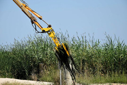 Pala de excavadora quitando plantas de agua de una zanja de drenaje.