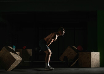 Fototapeta na wymiar High contrast side view photo of a healthy fitness guy doing workout using a kettlebell