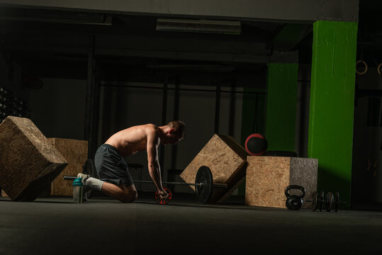 Shirtless pro athlete doing russian twist abs workout. Close up photo of a fit male athlete doing indoor training.