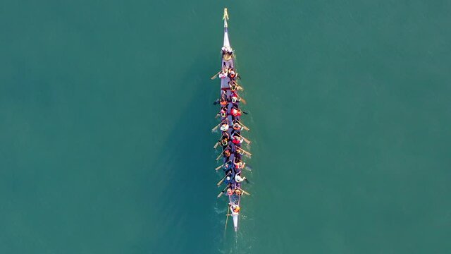 Dragon Boat team rowing to the pace of an onboard Drummer, Aerial view.
