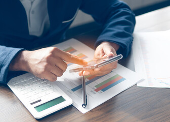 Businessman working on desk office analyze document in his hands.Graphs and diagrams on Mobile...