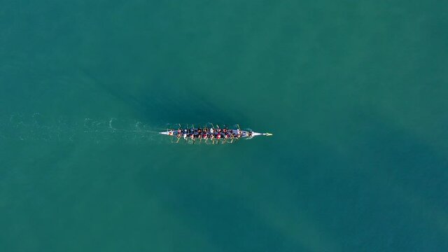 Dragon Boat team rowing to the pace of an onboard Drummer, Aerial view.
