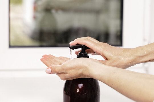 a woman squeezes the shapoo gel onto her hands from a bottle with a dispenser