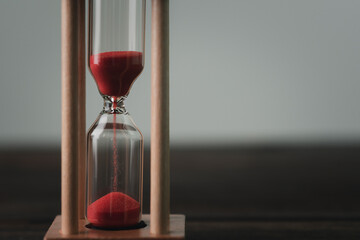 An hourglass rests on a wooden floor.