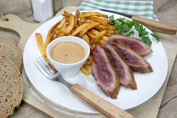 magret de canard grillé et frites dans une assiette