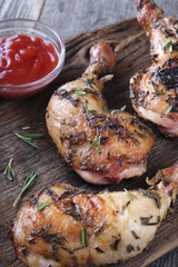 Grilled chicken legs in a white round plate on a wooden table. Vertical image