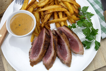 magret de canard grillé et frites dans une assiette