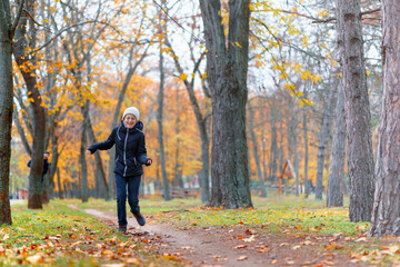 teen girl and boy running through the park and enjoys autumn, beautiful nature with yellow leaves