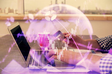 Double exposure of man hands holding a credit card and Forex graph drawing. Stock trading and digital fintech in Internet E-commerce concept.