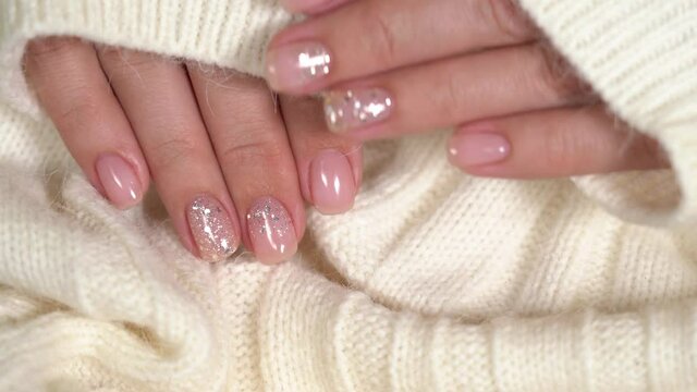 Elegant manicured hands of woman isolated on white background. Pink and silver nails on fluffy texture of jumper. Winter time and beauty concept.