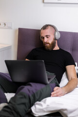 Man in bedroom on bed fell asleep in front of laptop 