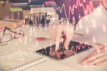 Double exposure of man's hands holding and using a digital device and forex graph drawing. Financial market concept.