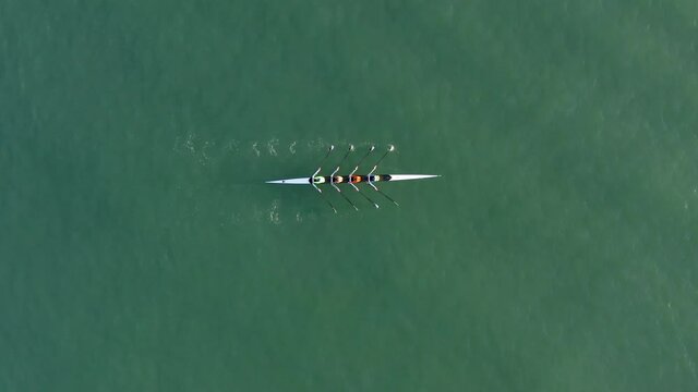 Sport Canoe with a team of four people rowing on tranquil water, Aerial view.