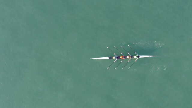 Sport Canoe with a team of four people rowing on tranquil water, Aerial view.