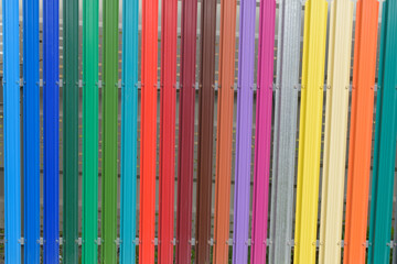 Multicolor metal fence. Vertical metal stripes are painted with paint.