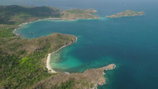 Aerial view coastline with tropical beach, island Limbones, lagoons and coral reefs. Neela cove, Philippines, Luzon. Coast ocean with turquoise water. Tropical landscape in Asia.