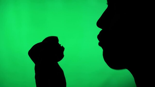 silhouette of a person on a green background. man bites and eats fruit or vegetables
