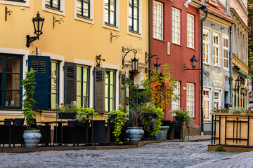 Medieval street with colourful houses, lanterns and plants in Riga Old Town during sunny autumn day is empty of tourists
