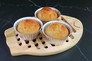 Fresh Baked Homemade Banana Muffins in Molds on a Wooden Breadboard	
