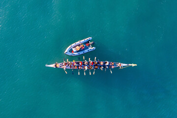 Dragon Boat team rowing to the pace of an onboard Drummer, Aerial view.