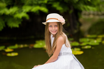 Beautiful girl playing on nature background. Smiling child looks in camera in summer park outdoor on a sunny day.