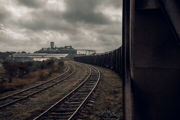 Obraz premium freight carriage for the transportation of bulk cargo, us against the background of a grain loading point. Grain storage bins on a cloudy sky background. THE USSR. freight train.