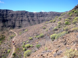 Hiking tourists on winding path during trip in mountains around Montana de Tauro in Gran Canaria, Canary Islands, Spain.