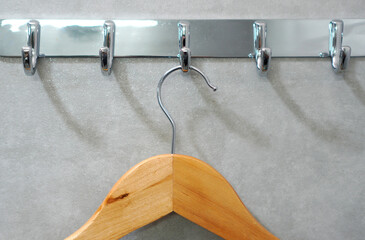 Wooden clothes hanger hanging on a chrome plated hanger.