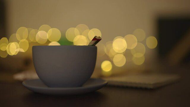 blue cup with hot cholate on table with christmas lights on background in dark evening light