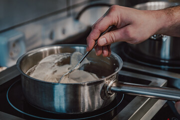Chef hand preparing cream sauce in pot