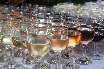 Many glasses of wine, of different colors, in row with a selective blur. Red, Rose and White wine are visible, from many varieties of grapes