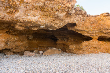 Beautiful natural cave near the shore. Prehistoric excavation on a stone beach. Neanderthal era.  