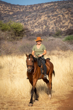 Blonde horsewoman in savannah rides towards camera