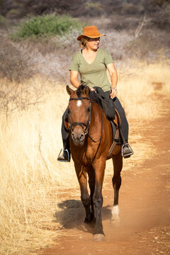 Blonde horsewoman rides looking right in savannah