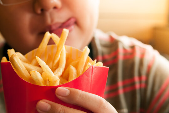 Closeup of hungry kid holding French Fries packet