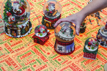 Hand decorating many Christmas snow globe balls on a table. Female putting festive Xmas dome balls...