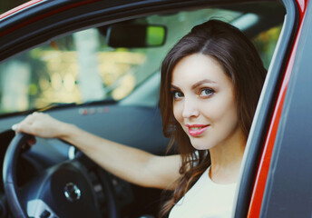 Fototapeta na wymiar Portrait of happy smiling woman driver behind a wheel red car