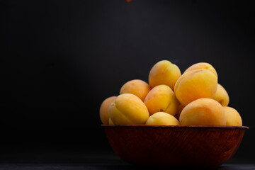 Apricots in a bowl on a black background