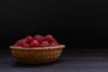 Raspberries in a basket on a black background