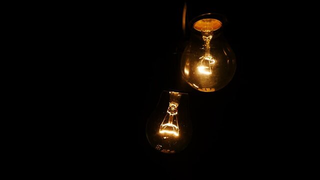 Close-up of a classic incandescent set of two lamp. Glass bulb, inert gas and tungsten filament. Soft natural light. Lamp velvet effect. Is flaring up brighter and brighter. Super macro.
