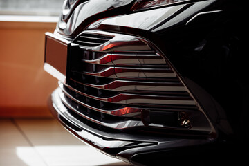 bumper of new luxury black car in salon, Titanium equipment, Led headlights dynamic drive, parking sensors, silver front grille mounted
