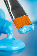 Paint brush and tube of opened blue acrylic pain
